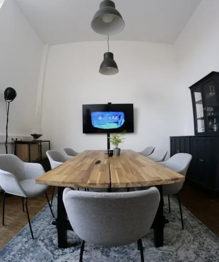 Besprechungsraum mit Holztisch, Stühlen und Bildschirm an der Wand