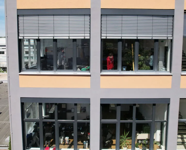 Fassade des Bürogebäudes in Stuttgart-Feuerbach mit großen Fenstern, dahinter Arbeitsplätze