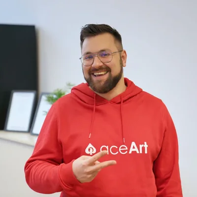 Florian Krüger, Geschäftsführer, im roten aceArt-Hoodie im Büro